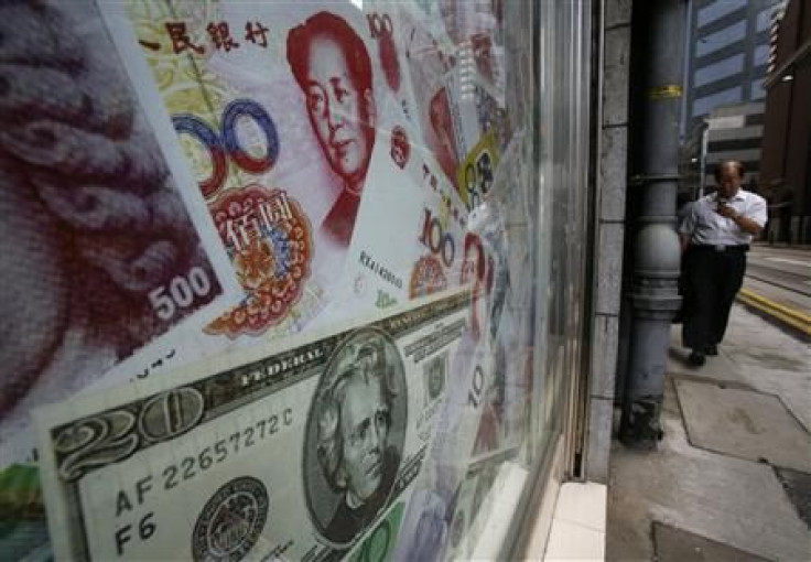 Photos of yuan and U.S. dollar banknotes are displayed at a money exchange in Hong Kong