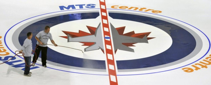 Ice technicians install the NHL&#039;s Winnipeg Jets logo at centre ice in Winnipeg
