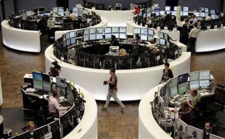 Traders work at their desks in front of the DAX index board at Frankfurt's stock exchange