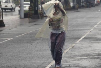 A woman uses a sheet of plastic to protect herself from rain brought by typhoon Nesat while walking along a main street in Manila