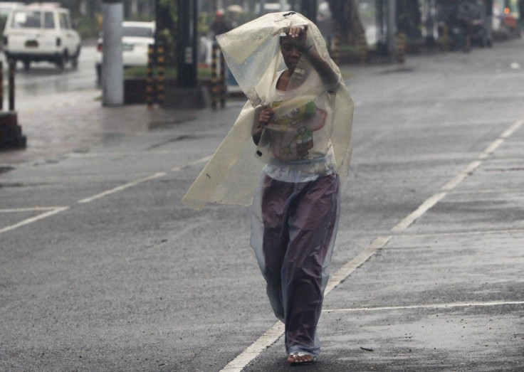 A woman uses a sheet of plastic to protect herself from rain brought by typhoon Nesat while walking along a main street in Manila