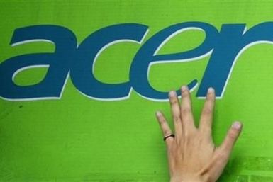 A man's hand is seen on an Acer logo as he pastes a poster below at a computer mart in Taipei