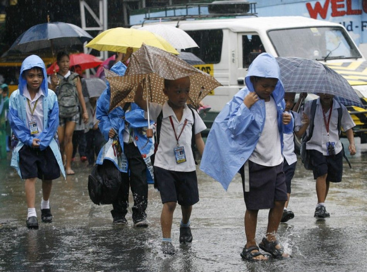 Students walk home in the rain after the suspension of classes due to rainfall from Typhoon Nesat in Quezon City