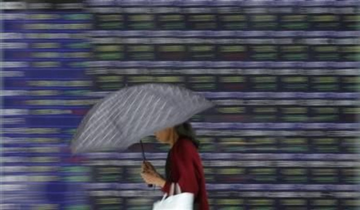 A woman walks past a stock quotation board outside a brokerage in Tokyo