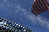 A Ford truck sits for sale under an American flag at a dealership lot in Encinitas, California