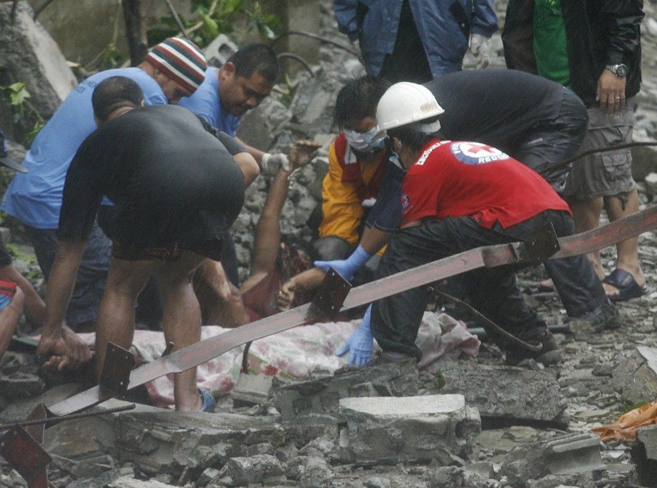Rescuers recover a body beneath the rubble after strong winds brought by Typhoon Nesat knocked down a wall killing four residents in Valenzuela City 27092011