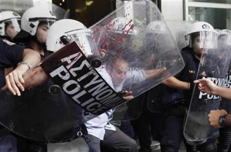 An employee of the Finance Ministry scuffles with riot police at the ministry&#039;s entrance in Athens during a protest against the government&#039;s austerity measures