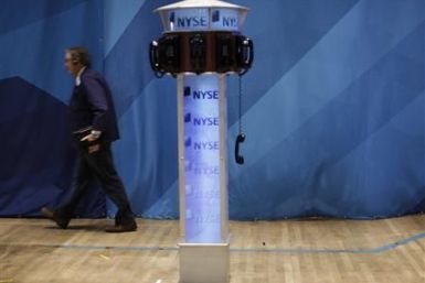 A trader walks past a phone hanging off the hook on the floor of the New York Stock Exchange