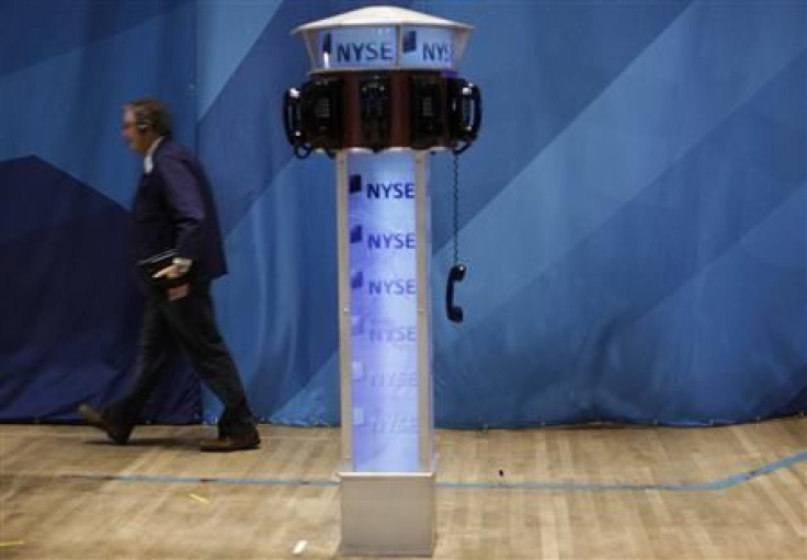 A trader walks past a phone hanging off the hook on the floor of the New York Stock Exchange