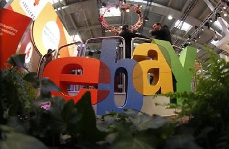 Visitors chat next to Ebay logo at CeBIT computer fair in Hanover
