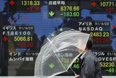 A man walks past a stock quotation board outside a brokerage in Tokyo