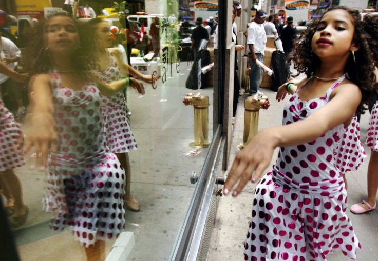 Girl from Amarilys Academy is reflected in shop window as she prepares for Puerto Rico Day parade in New York.