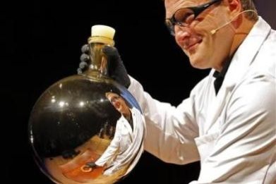 A chemist is reflected in a beaker after mixing chemicals that gave the beaker a reflective coating during a demonstration at the 21st annual Ig Nobel prize ceremony at Harvard University in Cambridge, Massachusetts