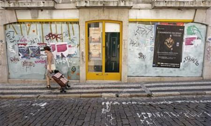 A woman pulls her shopping trolley in front of a closed shop in central Lisbon