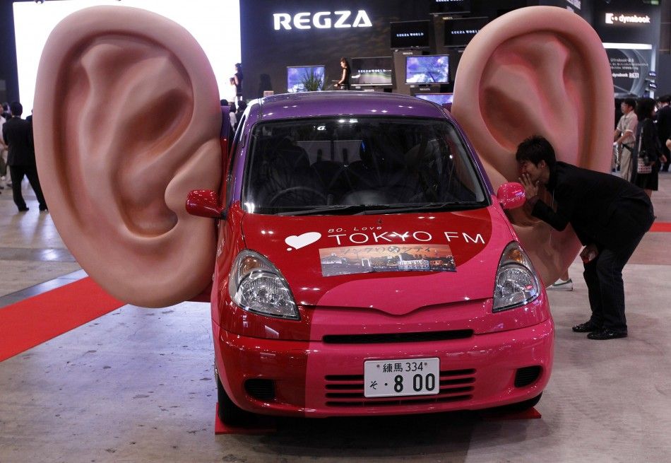 A man talks into a large model of a ear which has recording capabilities on a car at CEATEC JAPAN 2011 electronics show in Chiba, east of Tokyo