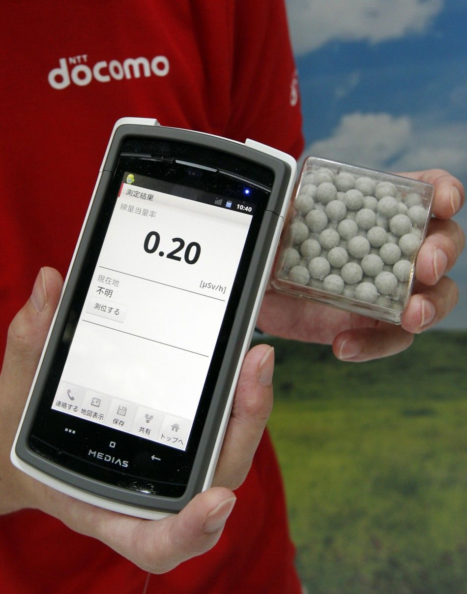A staff member of NTT DoCoMo holds a prototype of a smart phone case which measures radiation levels as demonstrated on radium balls R which contains a small amount of radiation at the CEATEC JAPAN 2011 electronics show in Chiba, east of Tokyo