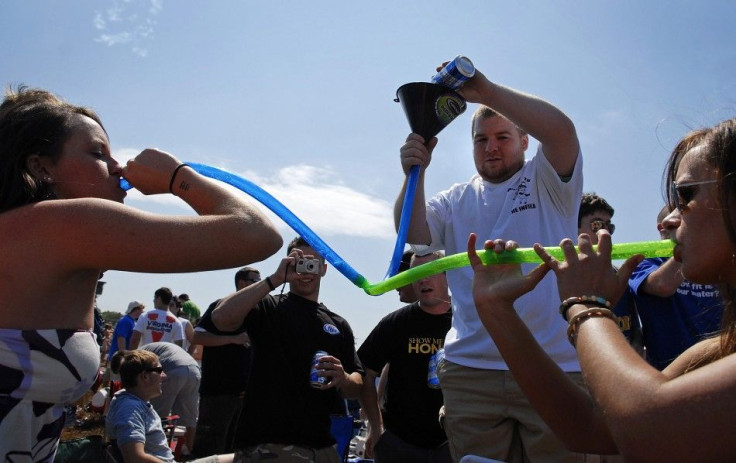 Young women drink beer from a twin-barrelled funnel before the Preakness Stakes in Baltimore