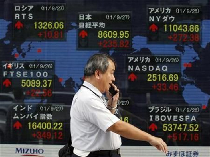 A man walks past a board showing the closing price of Japan&#039;s Nikkei share average along with other countries stock price indexes outside a brokerage in Tokyo