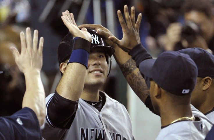 New York Yankees&#039; Jesus Montero is congratulated by teammates after scoring in the eighth inning of Game 4 in their MLB American League Division Series baseball playoffs in Detroit