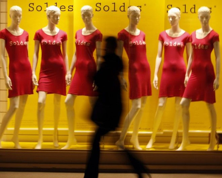 A shopper walks past a clothing store window advertising sales in Nice