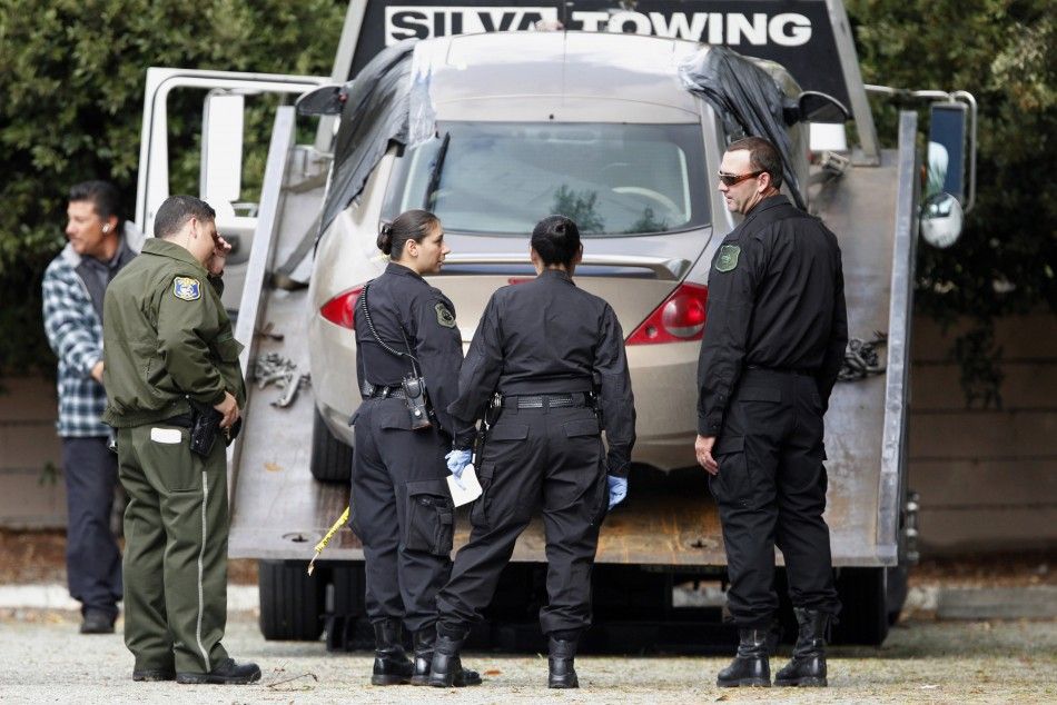 Santa Clara County Sheriff personnel stand around a vehicle of interest before it was transported away in the area near the Hewlett-Packard campus during a manhunt in Sunnyvale, California