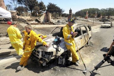 Emergency personnel lean against a burned out car at the site of a natural gas explosion in pipeline San Bruno, California September 11, 2010. 