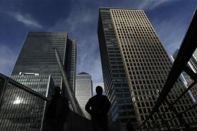 Silhouetted workers walk in front of office towers in the Canary Wharf financial district in London