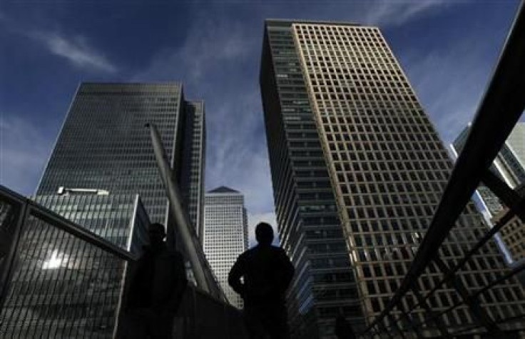 Silhouetted workers walk in front of office towers in the Canary Wharf financial district in London