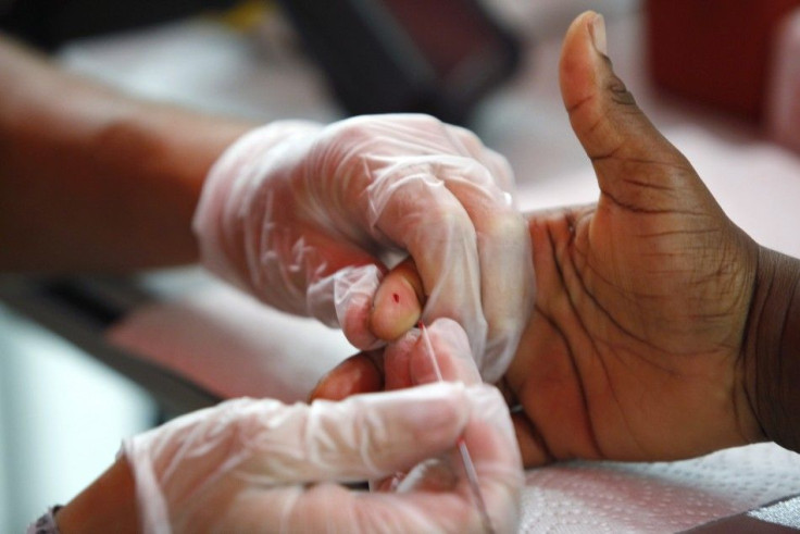 A medical technician draws a blood sample to screen for glucose and cholesterol.