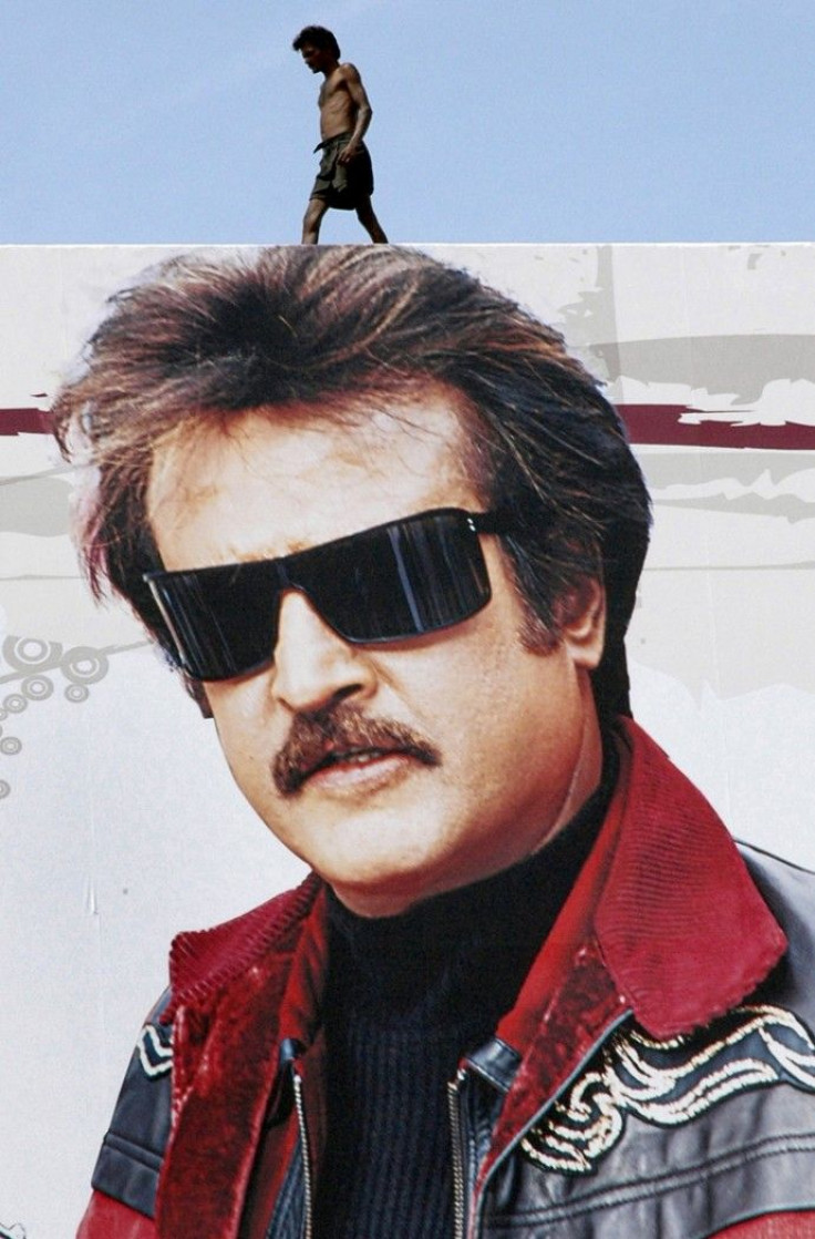 A worker walks pass a cutout of Rajnikanth