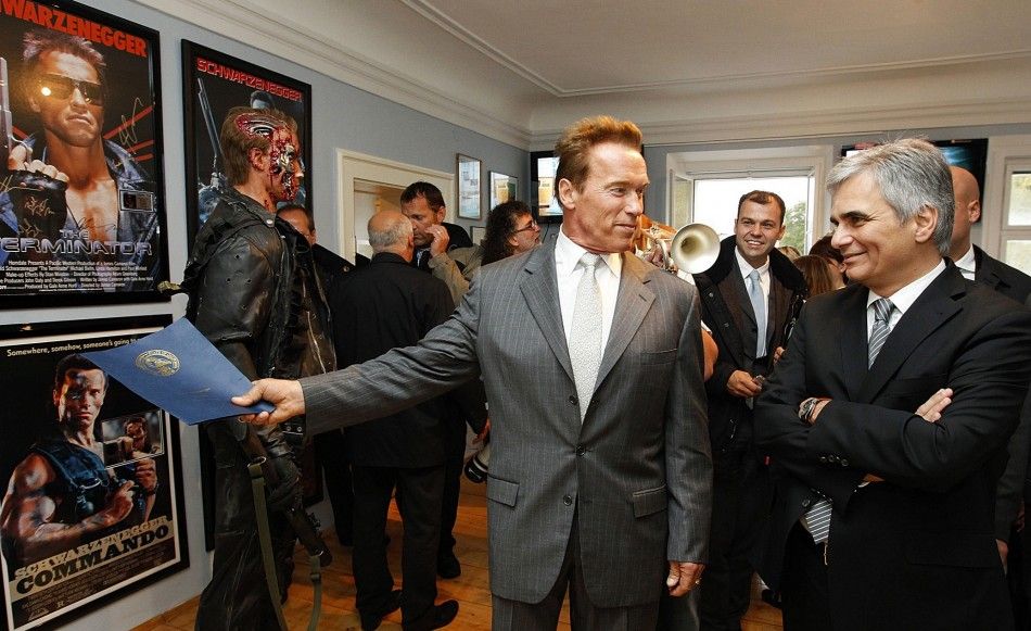 Austrian actor, former champion bodybuilder and former California governor Arnold Schwarzenegger C points at a Terminator film poster, as he chats with Austrian Chancellor Werner Faymann, during a tour of his former home in Thal 
