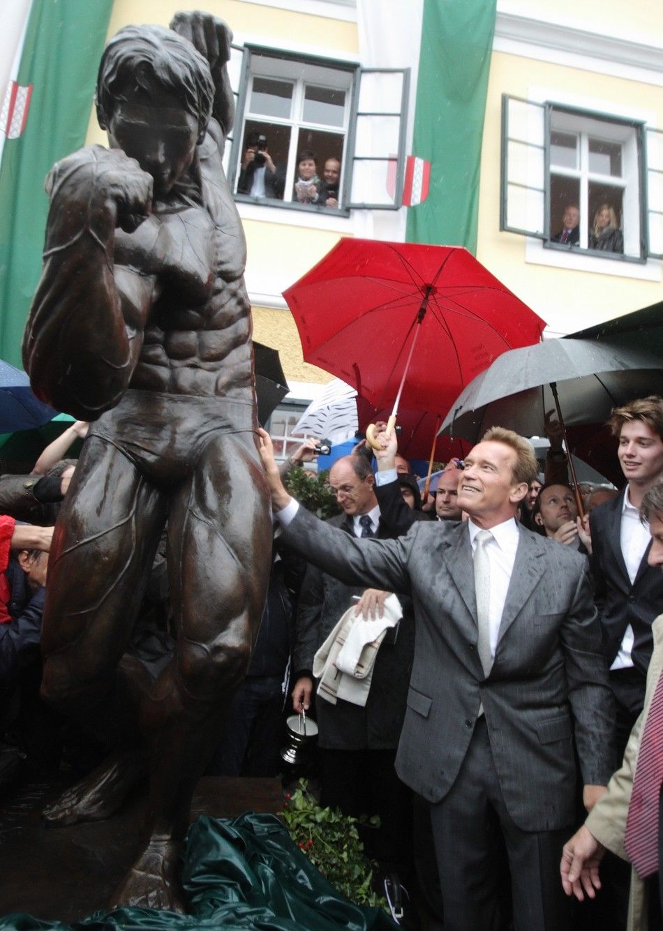 Austrian actor, former champion bodybuilder and former California governor Arnold Schwarzenegger, unveils a statue of himself in a bodybuilding pose as his son Patrick R watches, in Thal 