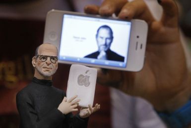 Artist Gennaro Di Virgilio holds an iPhone as he displays a model figure of Apple founder Steve Jobs in his shop in Naples 