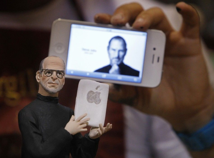 Artist Gennaro Di Virgilio holds an iPhone as he displays a model figure of Apple founder Steve Jobs in his shop in Naples 