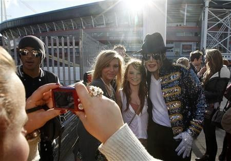 A Michael Jackson look-alike poses with fans as they queue for the ''Michael Forever'' tribute concert, which honours late pop icon Michael Jackson, at the Millennium Stadium in Cardiff, Wales