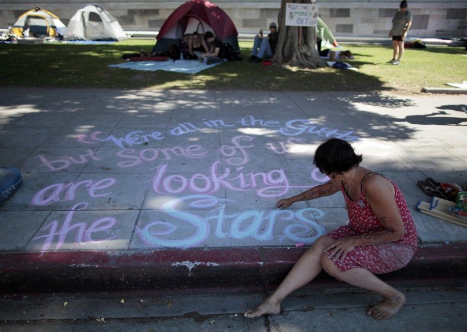 Susan Cameron, 49, writes messages in chalk on the sidewalk at the Occupy LA protest camp in Los Angeles, California