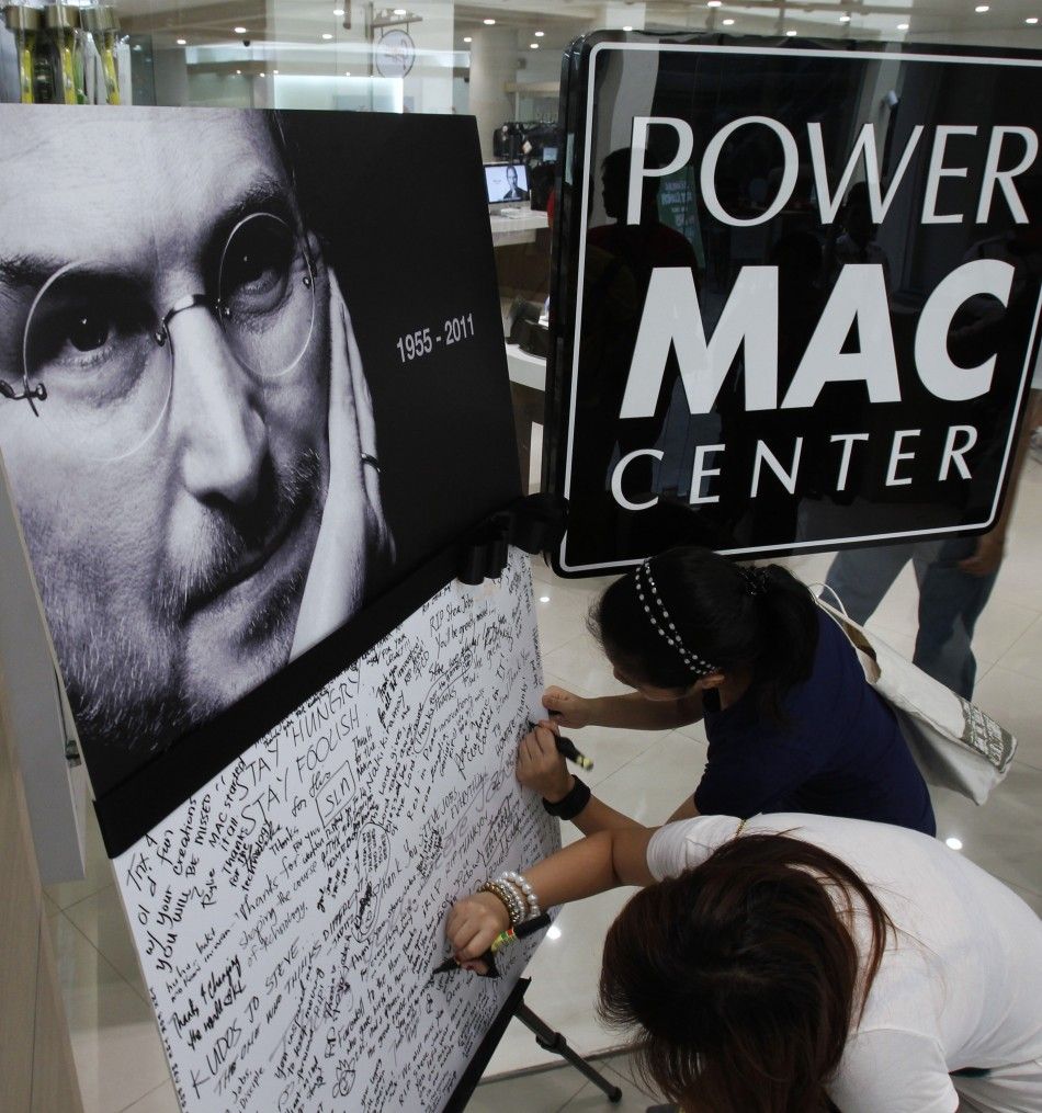 Women sign their names on a sympathy board set up for Apples co-founder Steve Jobs inside a Power Mac store in Manila