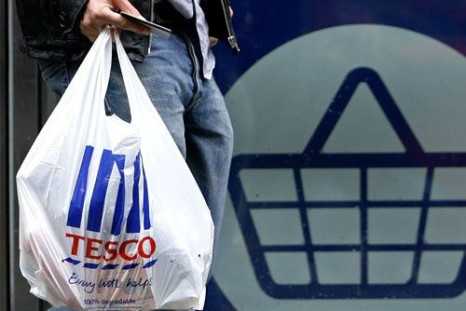 A man carries a carrier bag as he leaves a Tesco supermarket in London