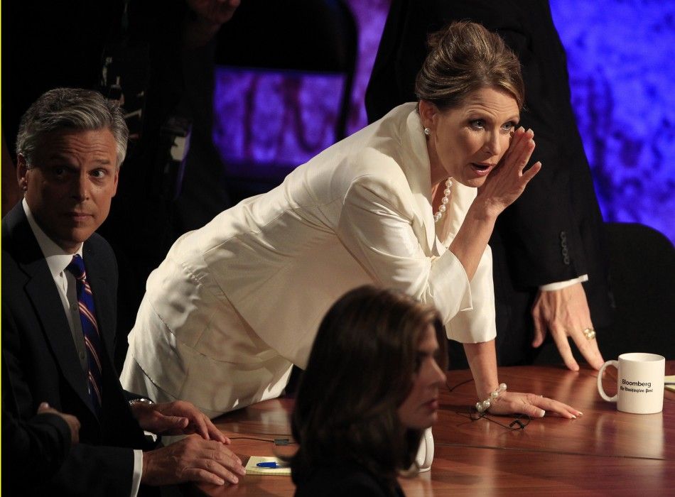 Republican presidential candidate, U.S. Rep. Michele Bachmann R-MN whispers to moderator Charlie Rose during a break next to former Utah Governor Jon Huntsman L during a Republican presidential debate at Dartmouth College in Hanover, New Hampshire 