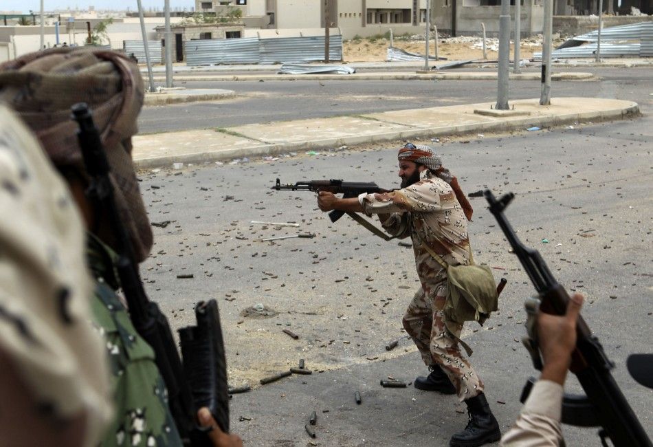 An anti-Gaddafi fighter shoots his gun during clashes with Gaddafi forces in Sirte