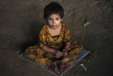 A three-year-old homeless Hindu girl, is photographed as she sits on a board game while taking shelter under a bridge in Karachi