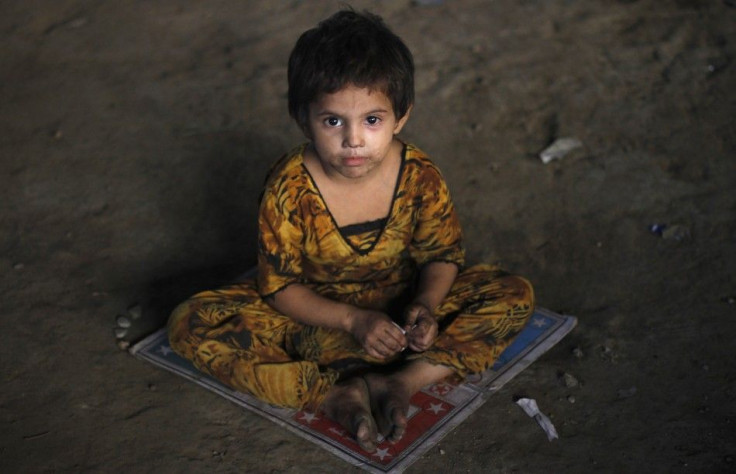 A three-year-old homeless Hindu girl, is photographed as she sits on a board game while taking shelter under a bridge in Karachi
