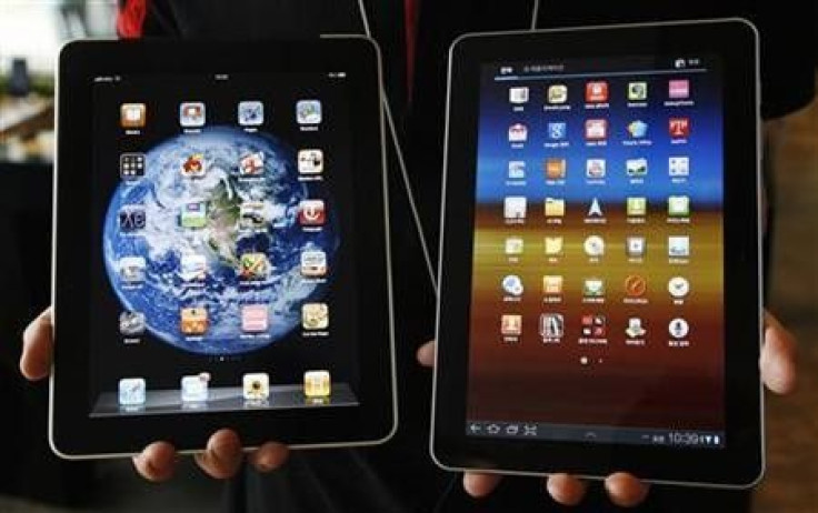 An employee of South Korean mobile carrier KT holds a Samsung Electronics&#039; Galaxy Tab 10.1 tablet (R) and Apple Inc&#039;s iPad tablet as he poses for photos at a registration desk at KT&#039;s headquarters in Seoul