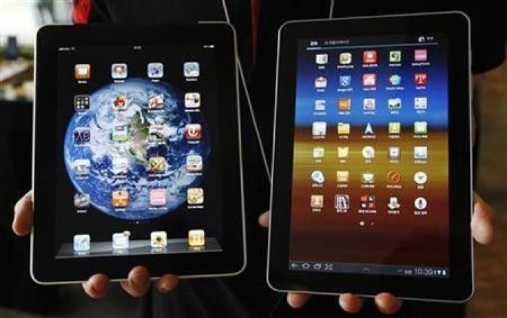 An employee of South Korean mobile carrier KT holds a Samsung Electronics' Galaxy Tab 10.1 tablet (R) and Apple Inc's iPad tablet as he poses for photos at a registration desk at KT's headquarters in Seoul