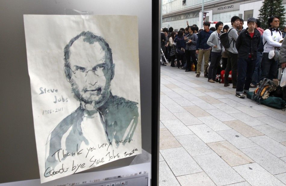 An image commemmorating Apple co-founder Steve Jobs is seen near customers queueing to buy iPhone 4S outside an Apple shop in Tokyo