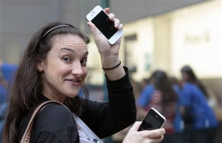 A customer shows off her new iPhone 4S as she leaves an Apple Store in New York