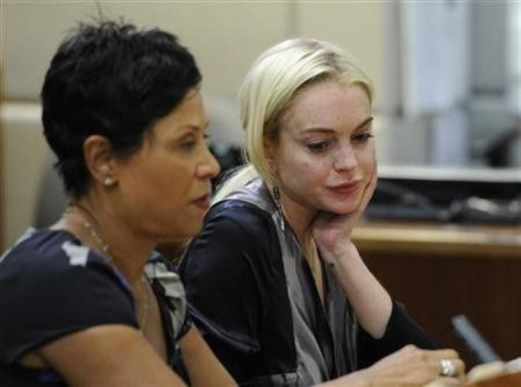 Actress Lindsay Lohan (R) sits in court with her lawyer Shawn Chapman Holley, during a compliance check to report her progress on 480 hours of community service she must do for shoplifting a necklace from a Venice jeweler, in Los Angeles, California