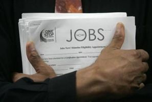 Man carrying a stack of job listings listens to a discussion at the One Stop employment center in San Francisco