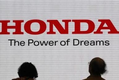 Visitors are silhouetted against a Logo of the Honda Motor at the company showroom in Tokyo