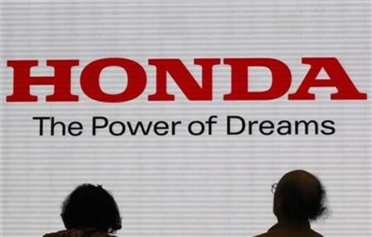 Visitors are silhouetted against a Logo of the Honda Motor at the company showroom in Tokyo